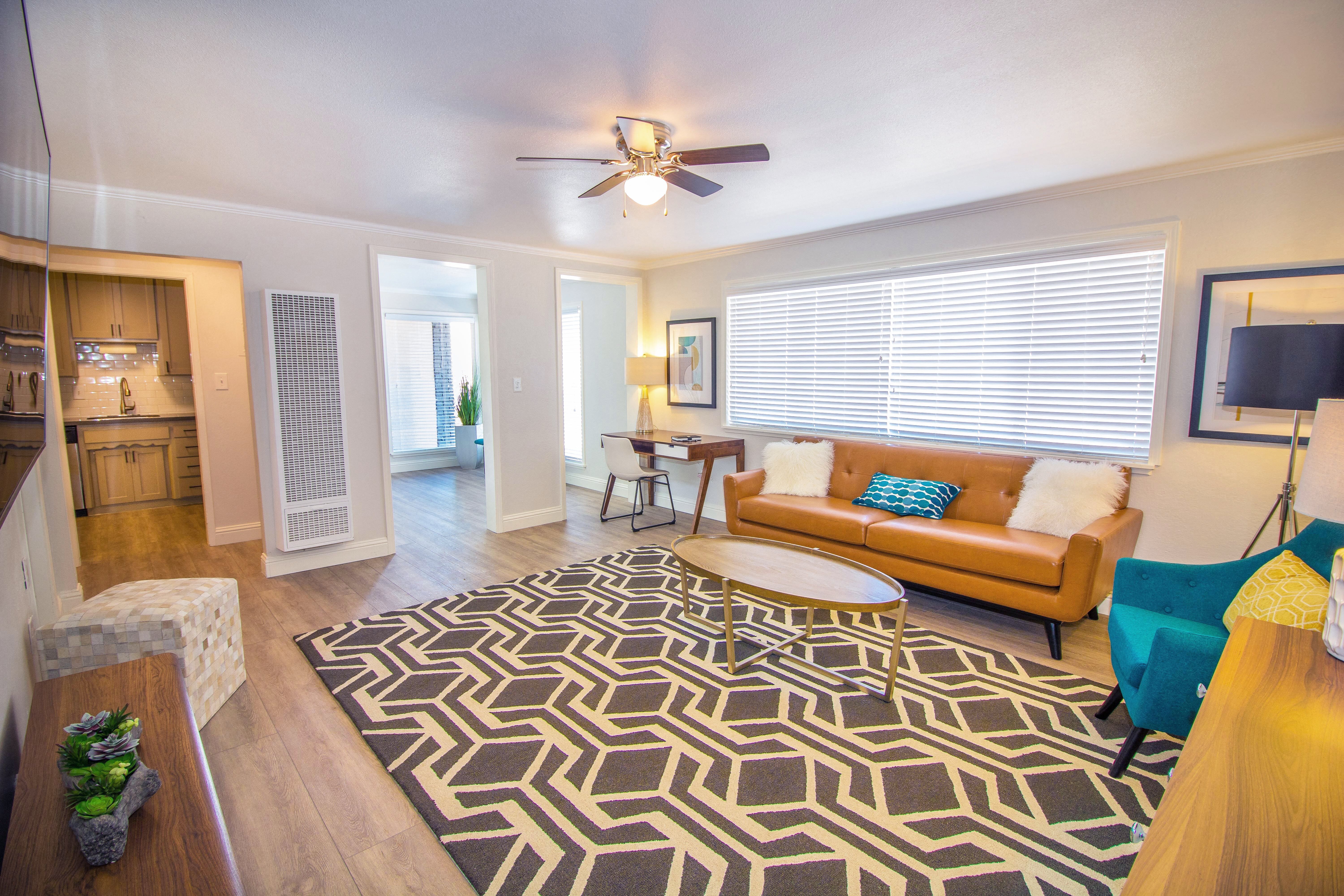a living room with a ceiling fan and a rug at Woodland Village Apartments , California